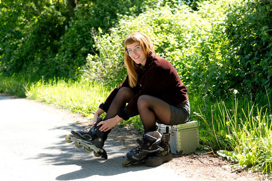 Portrait of young woman putting on inline skates