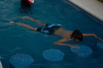 child looking down prone position doing little busts in the water while learning to swim is...