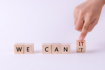 Woman hand flip wooden cube " . 'T" form " WE CAN'T " to " WE CAN IT " Motivation concept.