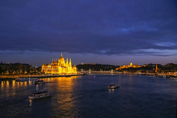 Fototapeta na wymiar Brightly lit palace of the Hungarian Parliament and the bridges on the Danube at night