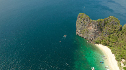 aerial view tropical beach on island with palm trees, blue lagoon and azure clear water. Helicopter Island in El Nido, Palawan Philippines. Tropical landscape with blue lagoon, coral reef