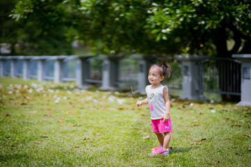 Asian toddler girl running in the park at the spring or summer day.