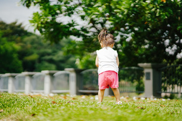 Asian toddler girl running in the park at the spring or summer day.