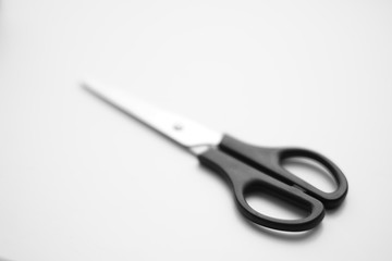Scissors with a black handle are on the white surface.