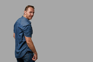 Fototapeta premium A man in a shirt shows with his hands on your text or your advertisement on a gray background. Concept banner for advertising, copy space, gray background, commercial design