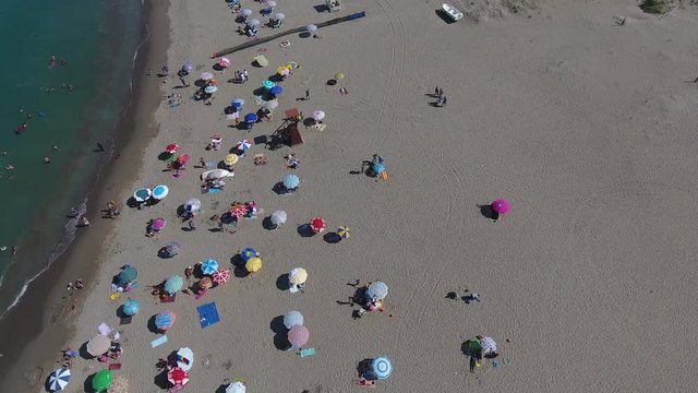 COLORFUL UMBRELLAS IN BEACH, CROWDED COAST FROM THE AIR