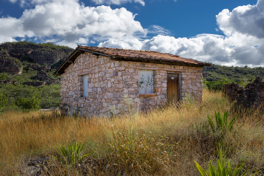 Stone country house in a green, a hill and cloudy sky. Igatu, chapada diamantina, Bahia, Brazil.