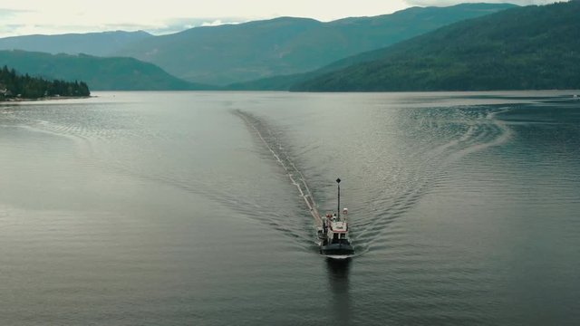 Aerial Drone Shot of Canadian Logging Tug Boat Pulling Logs & Timber Through Shuswap Lake, British Columbia, Canada. Logging Industry Forestry 