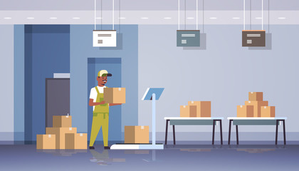 african american courier man in uniform putting parcel box on scales mail express delivery logistic service concept modern warehouse interior flat horizontal full length