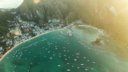 Many boats in the turquoise lagoon at sunset. Seascape with blue bay and boats view from above. El nido, Palawan, Philippines. traditional Filipino wooden outrigger boat called a banca. Summer and