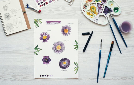 Watercolor painting of purple flowers on the desk, top view