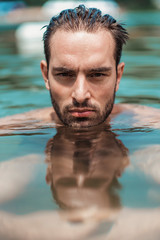Desirable young guy emerging from water