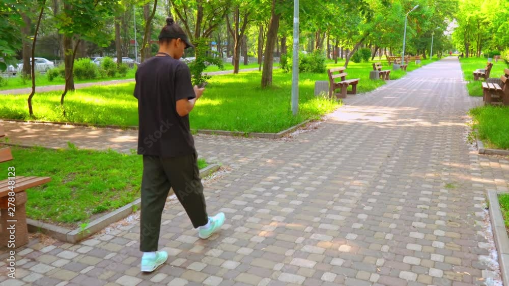 Poster side view man wearing casual trendy clothes walking on the street in spring season. student using sm