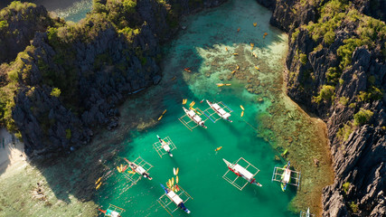 Tourist boats over tropical lagoon and coral reef, aerial view. Small lagoon with turquoise water. El nido, Philippines, Palawan. Summer and travel vacation concept.