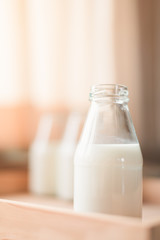 Fresh milk bottles without cap on wooden box near the window. A healthy drink concept. Copy space wallpaper.