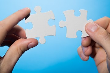 Closeup on Hands Combining Puzzle Pieces Together