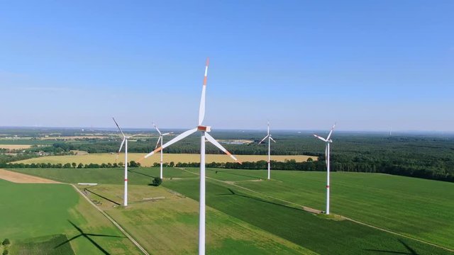 Aerial drone view of five wind power turbines, part of a wind farm, on a green field in eastern Germany near the city of Cottbus, Brandenburg. Wind turbines are part of the energy transition strategy.