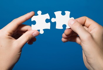 Closeup on Hands Combining Puzzle Pieces Together