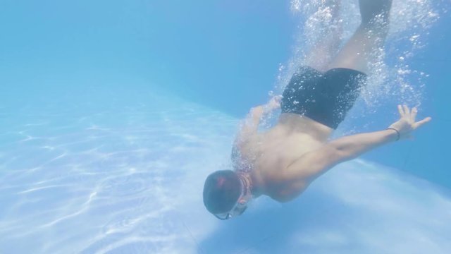 Young bearded man is diving in swimming pool in his vacation on tropical island.
