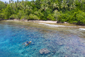A villager paddles his outrigger canoe in the warm, blue waters surrounding the island of New...