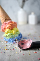 Melting rainbow ice cream waffle cone and scoop. Close up.