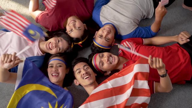 excited asian young supporter holding malaysia flag over isolated background