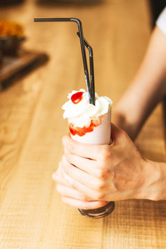 White ice cream in paper cone in hands