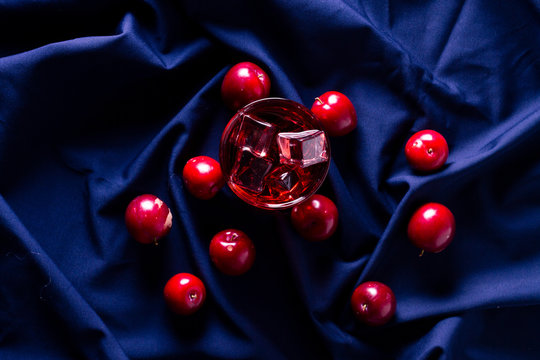 Red beverage near fresh fruits on cloth