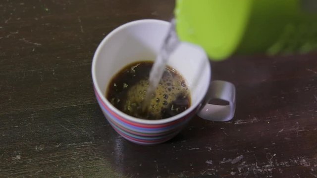 TOP SHOT POURING HOT WATER OVER A MUG WITH INSTANT COFFEE