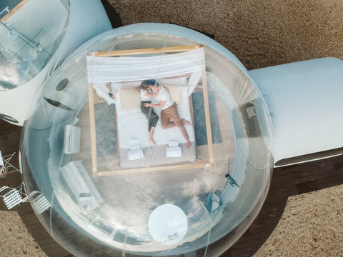 drone view of Passionate couple lying on bed in bubble hotel