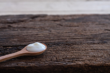 Natural homemade plain organic yogurt in wooden bowl and wood spoon on wood texture background