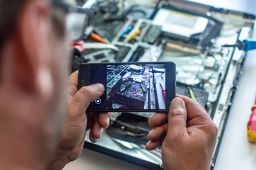 a man repairs a computer, solders a board, repairs electronics and modern technologies