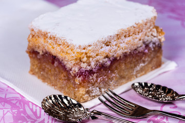 Raspberry and Coconut Slice on a white napkin with two fancy spoon and a fork