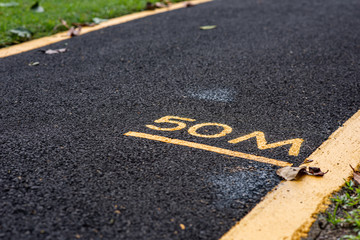 50M (meters), with yellow letters and line marked on a asphalt running track