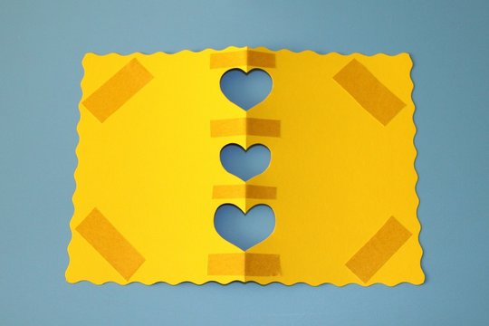 congratulatory postcard yellow paper with cut out hearts on a blue background