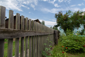 old fence in the background of the house and the blue sky