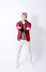 Young asian man wearing Christmas Hat and red jacket showing gesture sign. or laptop and Smartphone stand in isolated background