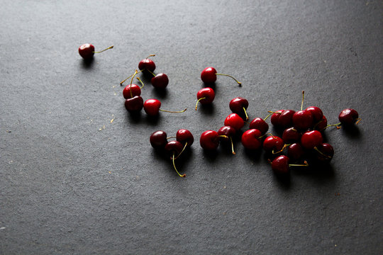 Shiny ripe red cherries on black background
