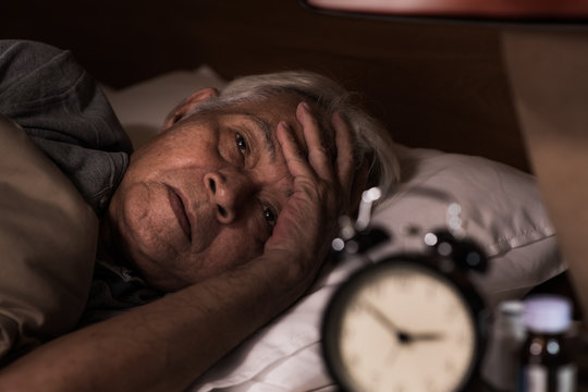 .Depressed senior man lying in bed cannot sleep from insomnia