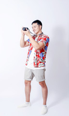 A Portrait of young tourist asian man wearing floral shirt and showing gesture sign. or laptop, Smartphone, camera  and wallet stand in isolated background