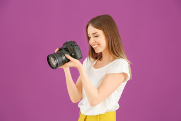 Young female photographer on color background