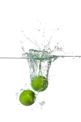 Falling of limes into water on white background