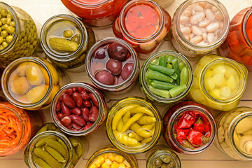 Jars with different canned vegetables on wooden background