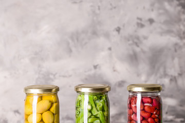 Jars with different canned olives and beans on grunge background