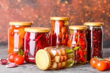 Jars with different canned vegetables on grunge table