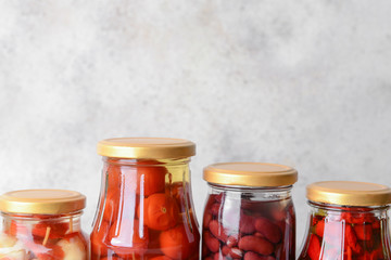 Jars with different canned vegetables and beans on grey background