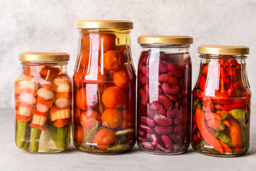 Jars with different canned vegetables and beans on grey table