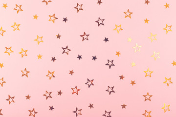 Festive background. Golden confetti stars on pink paper.
