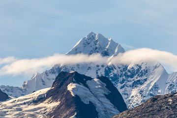 Naklejka premium Snowy mountain peak with clouds surrounding it in Glacier Bay, Alaska.