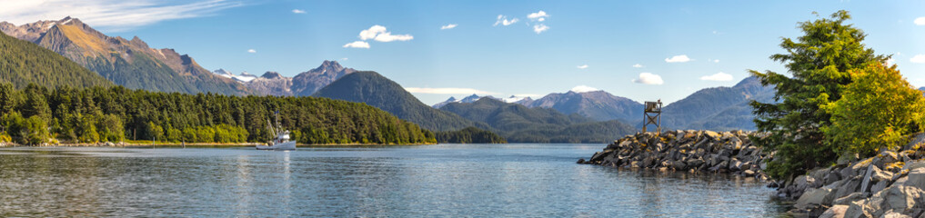 Panoramic view of the harbor with a fishing boat sailing in the distance in Sitka, Alaska. - obrazy, fototapety, plakaty